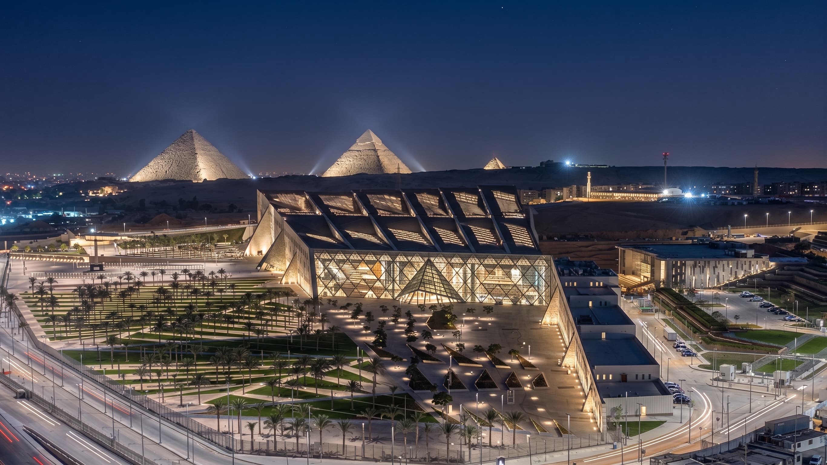 The monumental modern facade of the Grand Egyptian Museum (GEM) in Giza with pyramid-inspired design